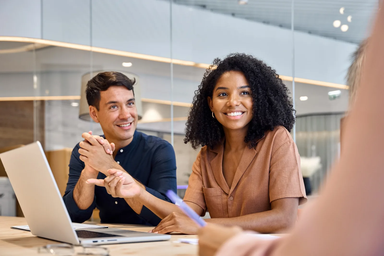 Two colleagues smile and listen during a meeting at a shared table