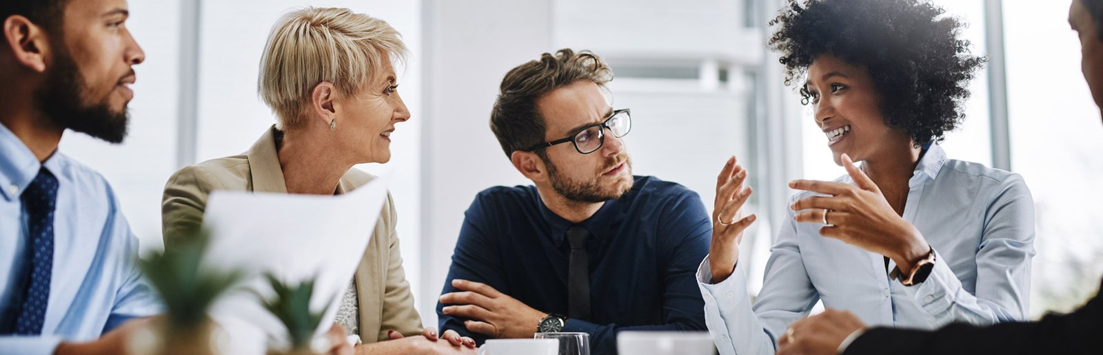 Four colleagues trade ideas around a meeting table